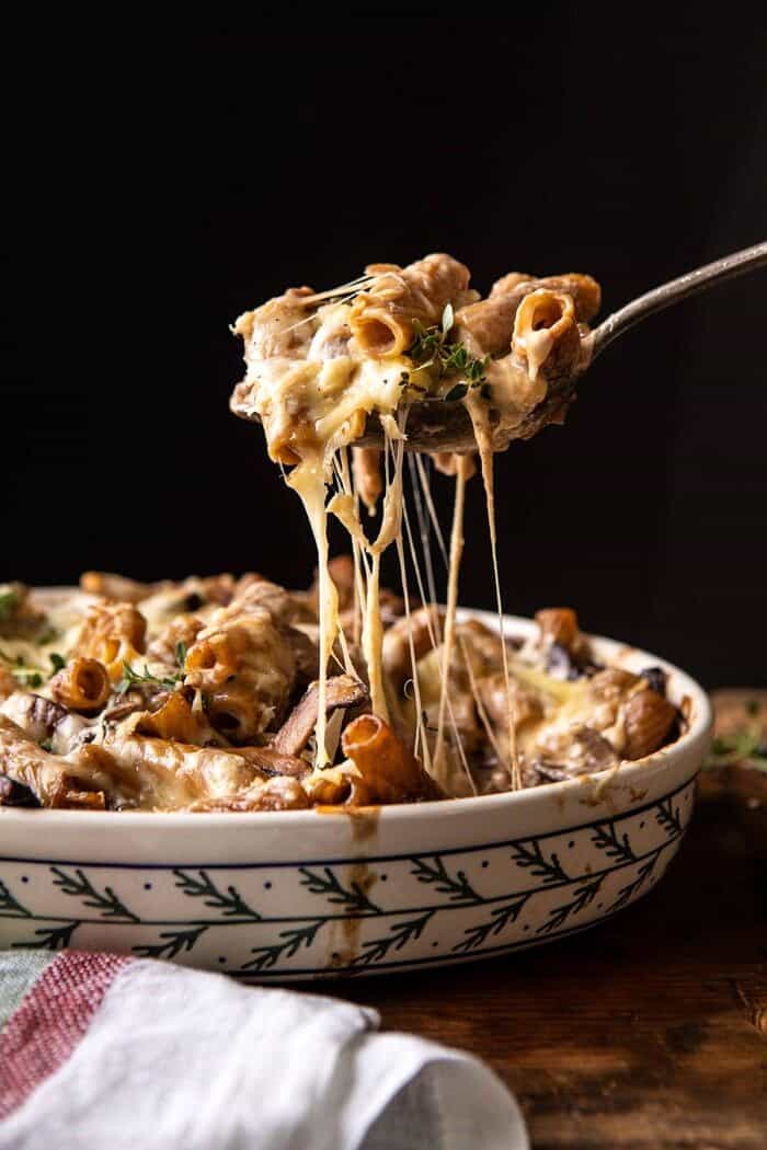 side angled photo of One Pot Creamy French Onion Pasta Bake with serving spoon pulling pasta out of the baking dish