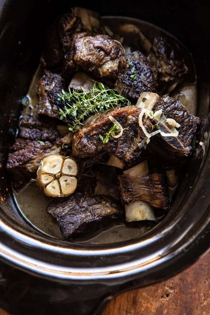 White Wine Braised Short Ribs with Buttered Mushroom Cream Sauce | halfbakedharvest.com #slowcooker #crockpot #shortribs #holiday #christmas overhead photo of White Wine Braised Short Ribs in crockpot bowl