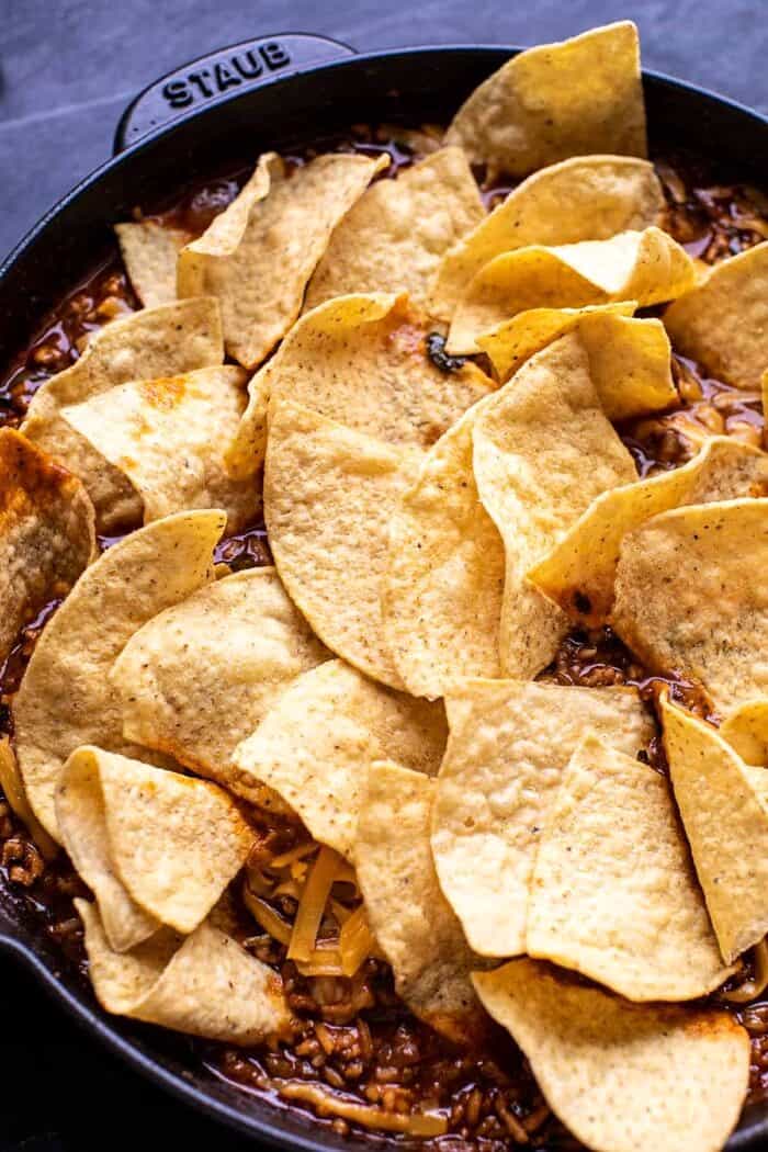 One Skillet Saucy Chicken Tortilla Enchilada Rice Bake | halfbakedharvest.com prep photo of skillet topped with chips before baking