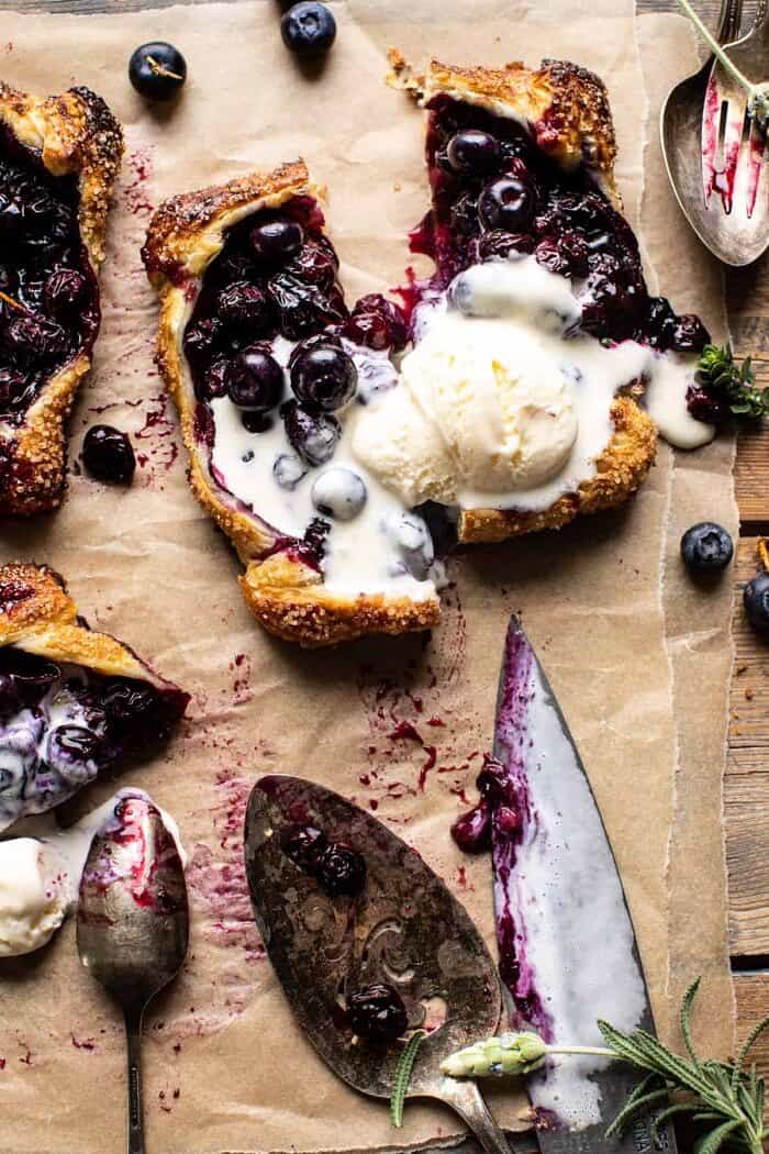 Bursting Blueberry Lemon Thyme Tarts | halfbakedharvest.com overhead photo of Bursting Blueberry Lemon Thyme Tarts cut in half with ice cream on top