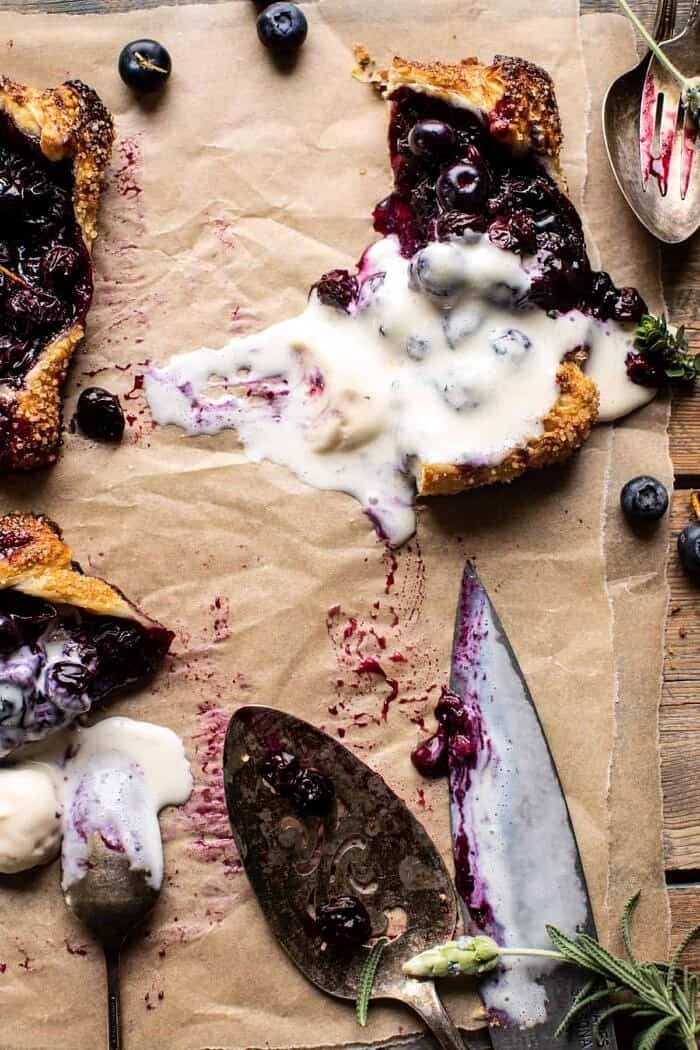 Bursting Blueberry Lemon Thyme Tarts | halfbakedharvest.com overhead photo of Bursting Blueberry Lemon Thyme Tart cut in half with ice cream melted on top
