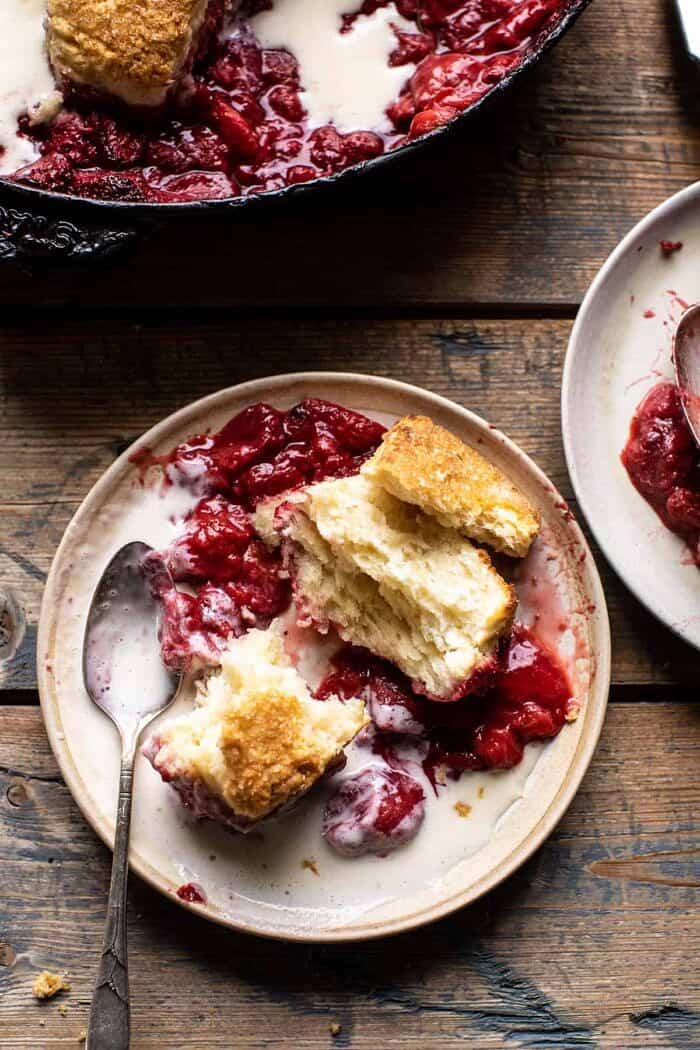 overhead photo of Skillet Strawberry Bourbon Cobbler with Layered Cream Cheese Biscuits on plate with spoon
