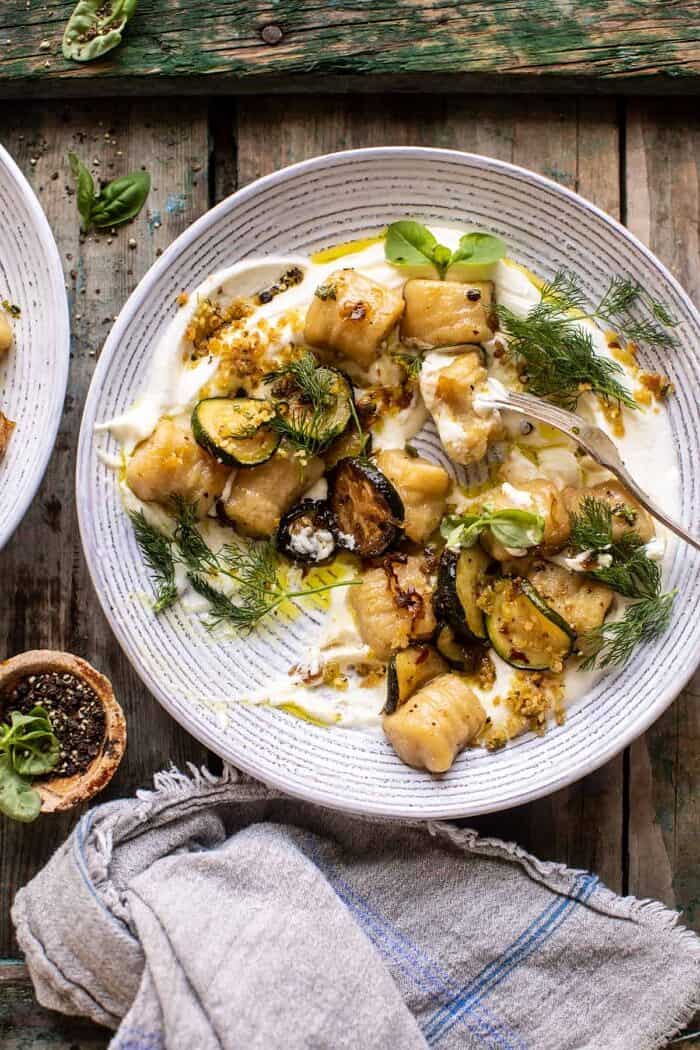 Cauliflower Gnocchi with Crispy Zucchini and Whipped Goat Cheese | halfbakedharvest.com overhead photo of Cauliflower Gnocchi with Crispy Zucchini and Whipped Goat Cheese and fork in bowl with cauliflower gnocchi eaten