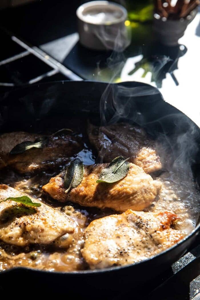 Browned Sage Butter Chicken Piccata with Mushroom Pasta | halfbakedharvest.com photo of Browned Sage Butter Chicken Piccata cooking on the stove in skillet