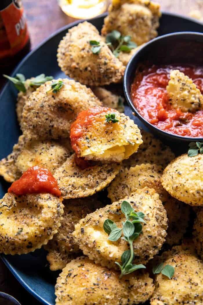 side angle photo of Oven Toasted Garlic Herb Cheese Ravioli with ravioli broken in half 