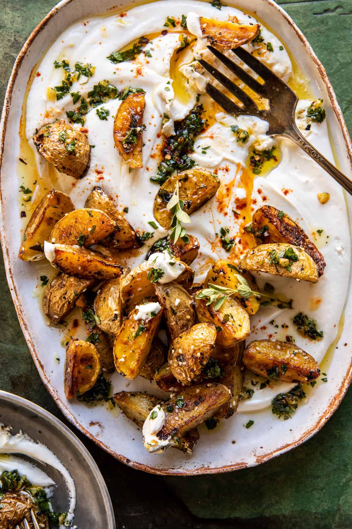 Crispy Oregano Roasted Potatoes with Creamy Feta Sauce on plate with fork 