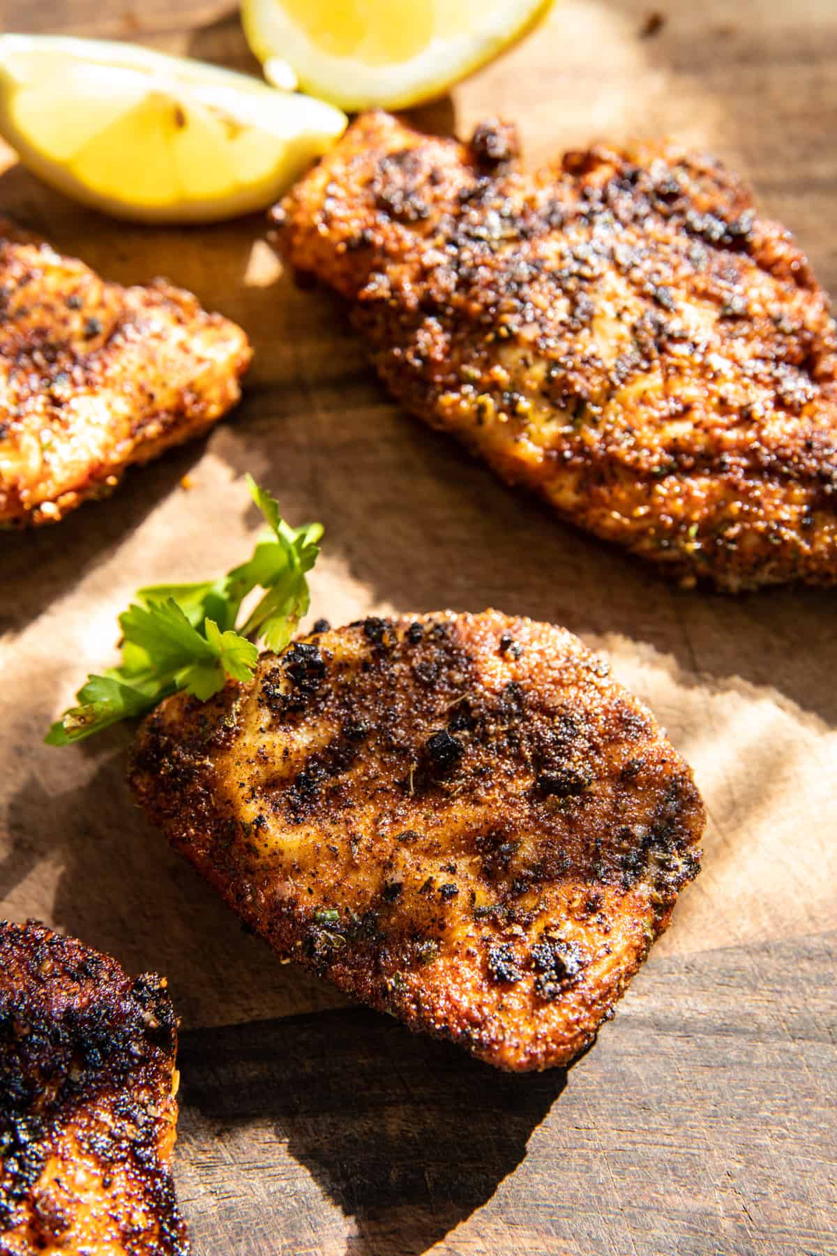 Lemon Pepper Cajun Chicken on a cutting board with lemons