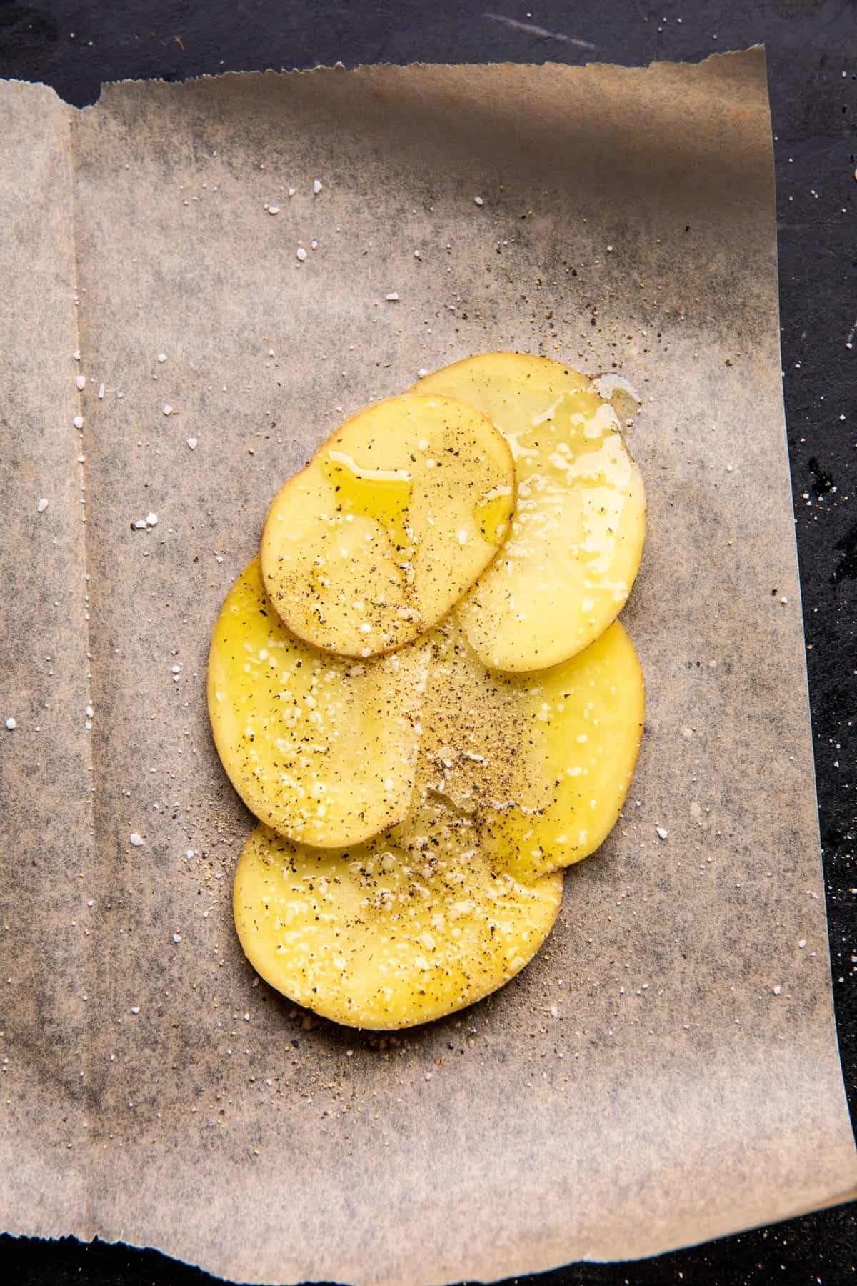 raw potatoes on parchment paper before adding salmon 