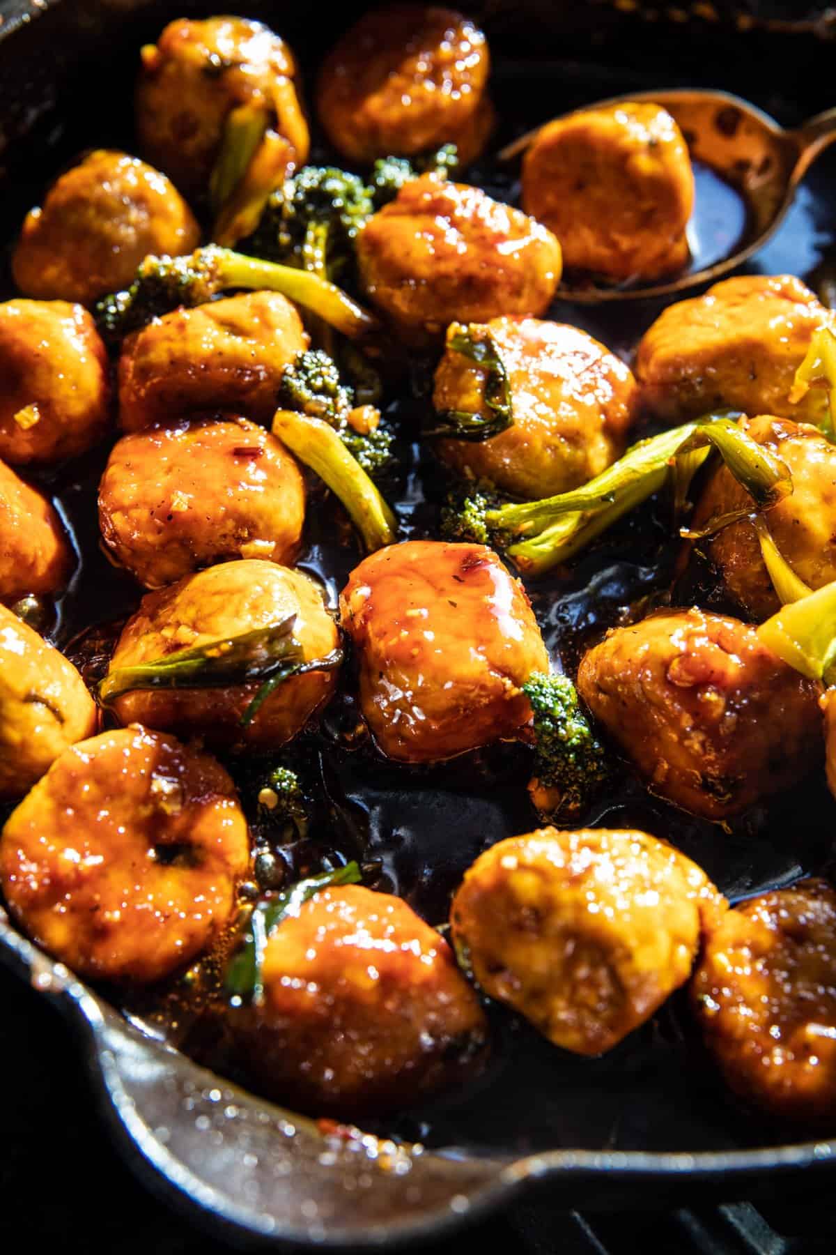 meatballs cooking in skillet with sauce and broccoli