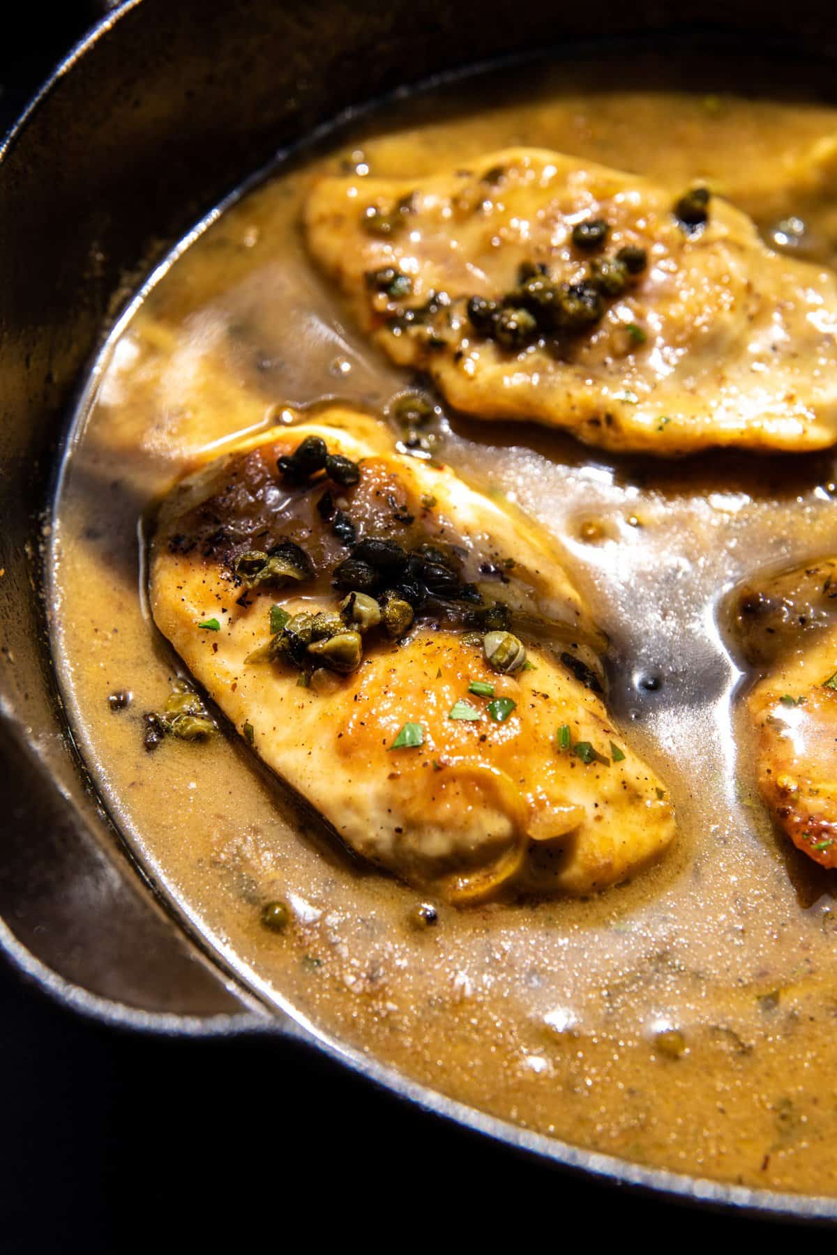 chicken cooking in skillet with lemon sauce